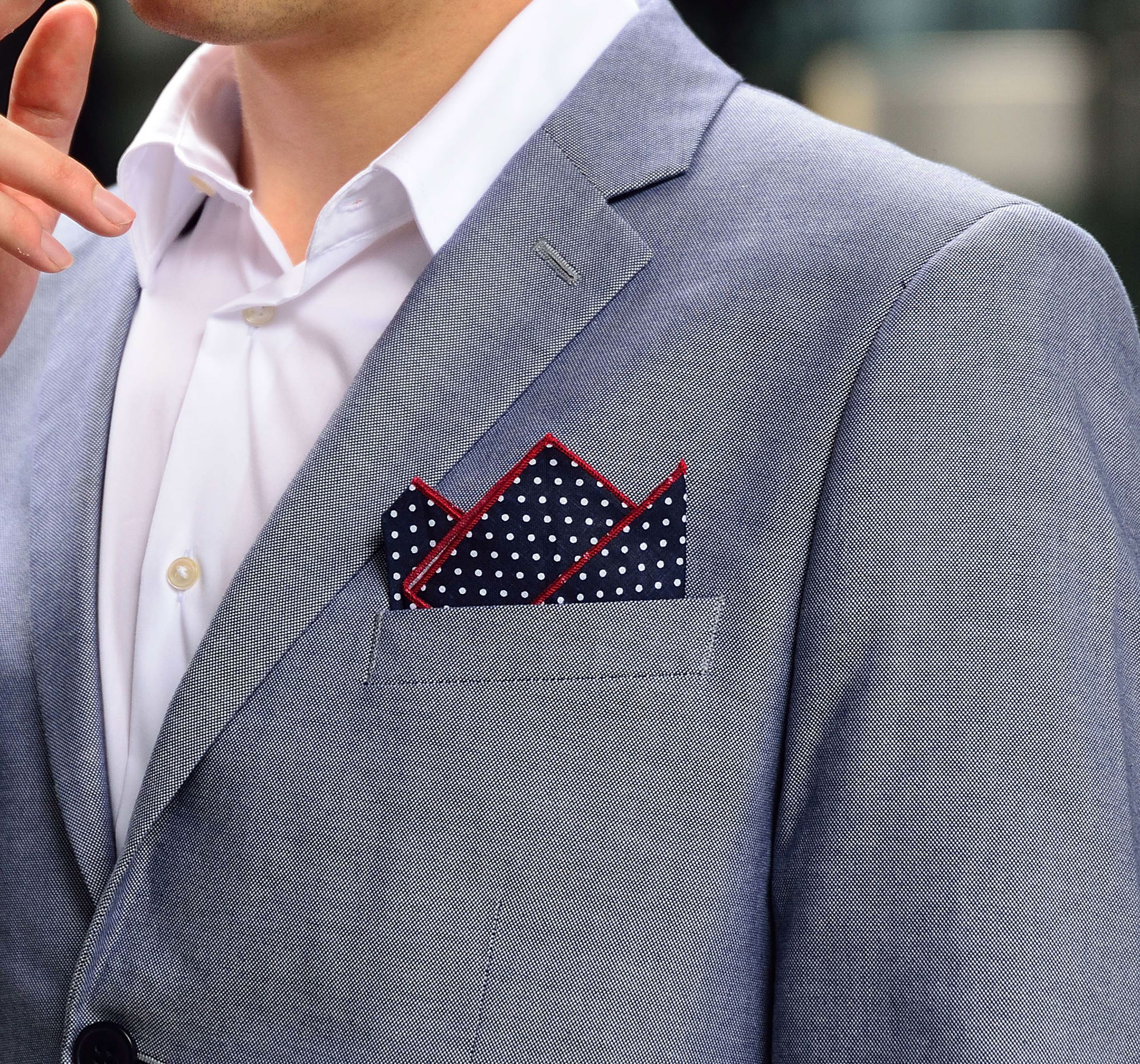 Four self-confident men wearing di Venisco pocket squares standing in front of a modern building.